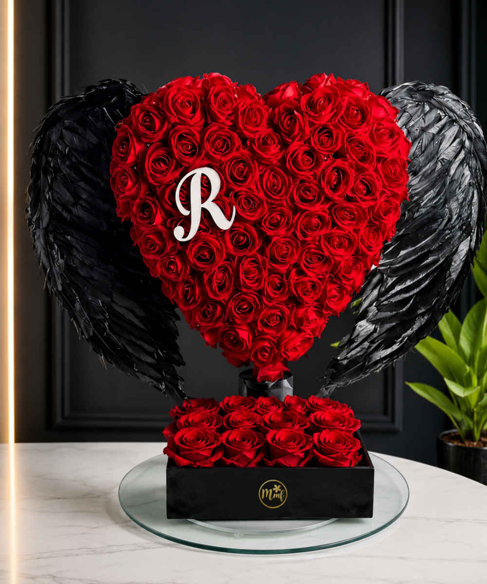 Luxury heart-shaped red rose arrangement with black angel wings, personalized initial, and premium black gift box for romantic gifting in Delhi NCR.
